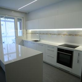 Cocina lacada en color blanco alto brillo con encimera blanca. sólo destaca el contraste de los electrodomesticos